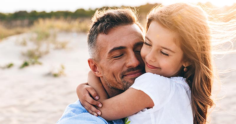 Father and daughter hugging at a beach