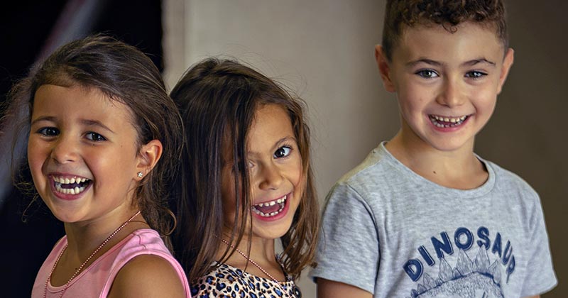 Three sibling children smiling